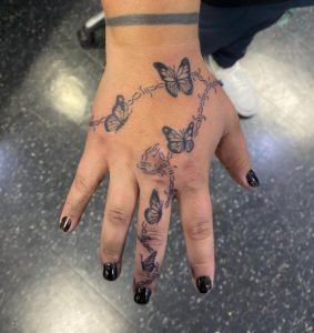 31 Outstanding Black Color Inked Butterflies Sitting on Barbed Wire Tattoo on Finger