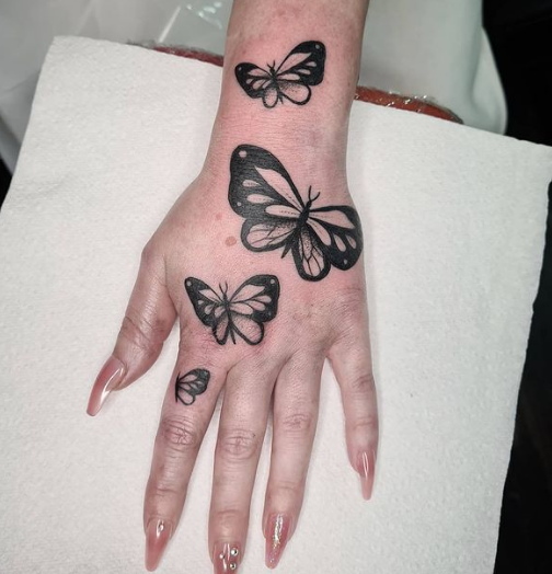 33 Lovely Black Color Inked Butterflies Tattoo Next to Fingers