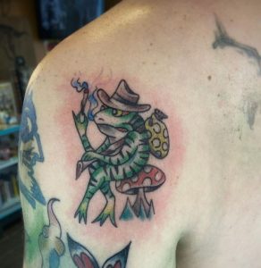 8 Cool Traditional Color Ink Designed Smart Frog is Relaxing Sitting on Mushroom Tattoo on Shoulder